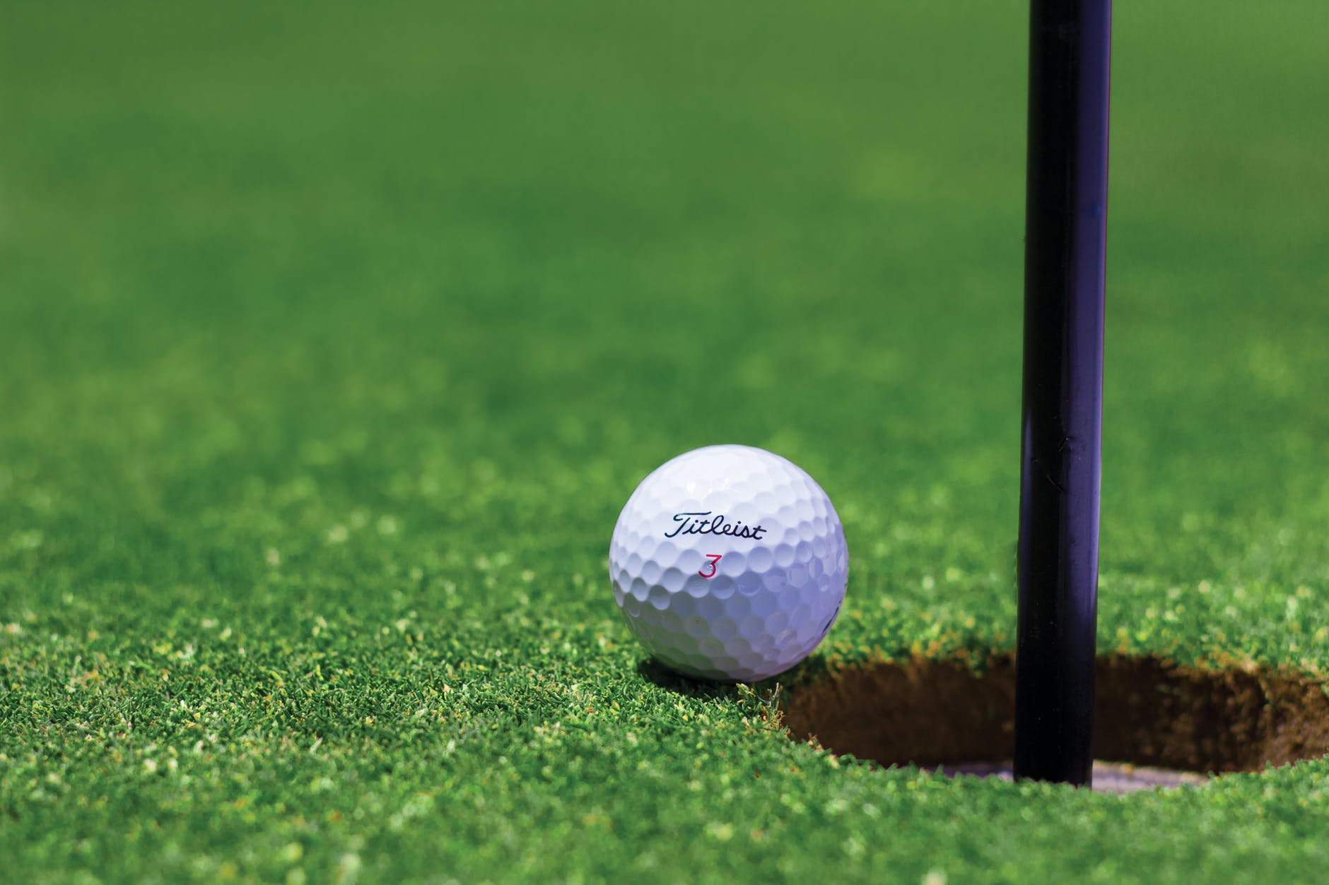 titrist golf ball near golf hole