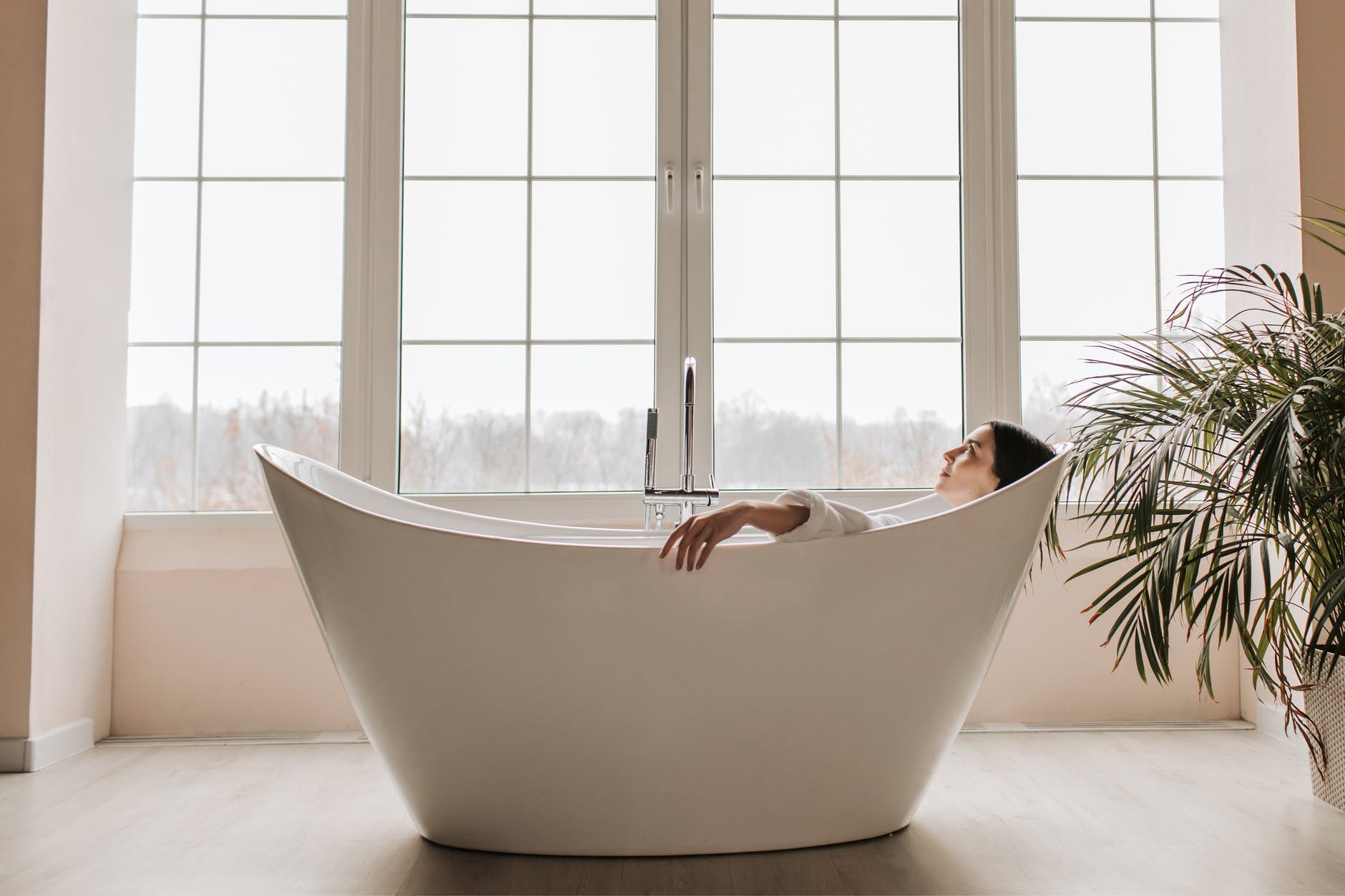 a woman lying in the bathtub near the glass window