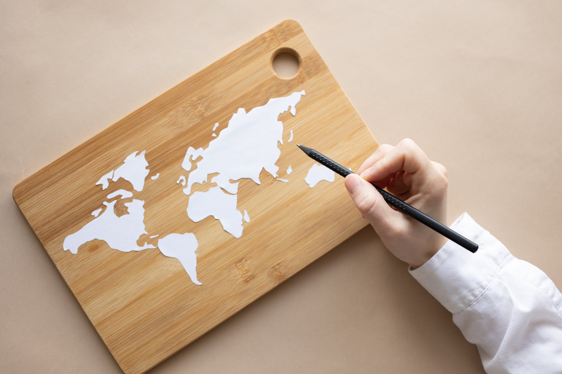 crop artist with white pencil drawing world map on desk