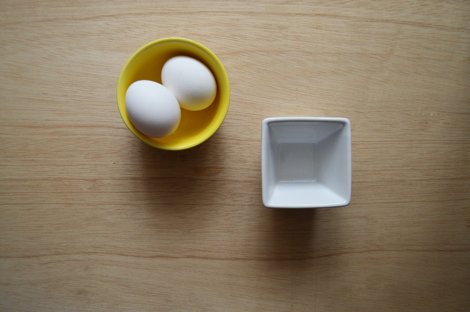 two white eggs in yellow ceramic bowl