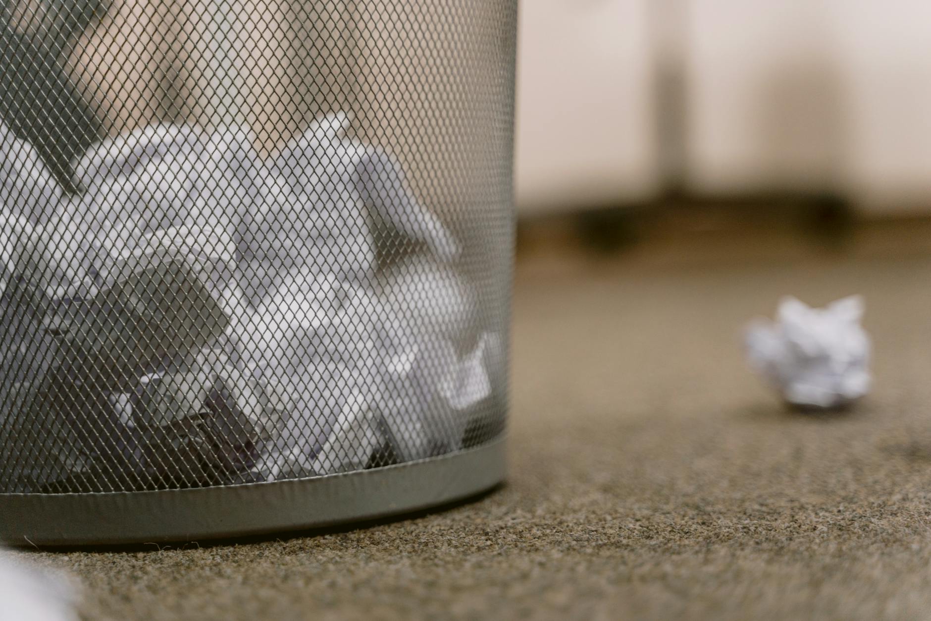 crumpled papers in a mesh trash can