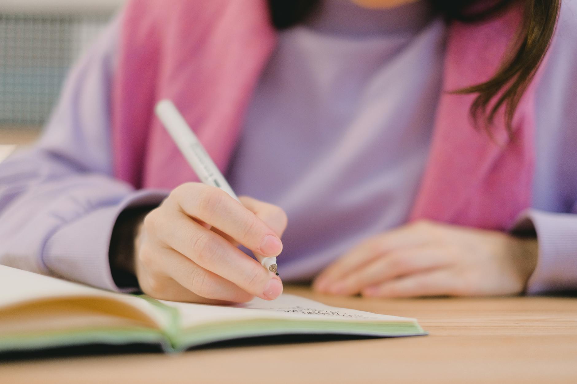 faceless female student writing in notebook during lesson