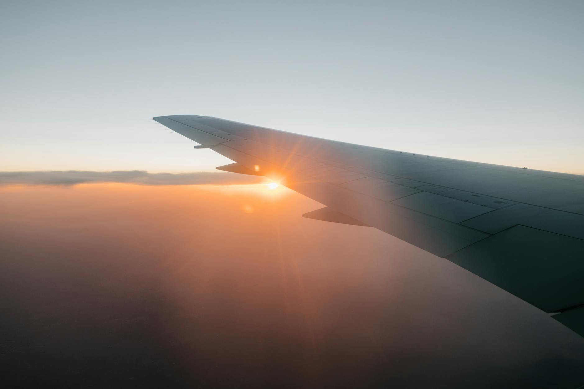 wing of airplane flying against sunset